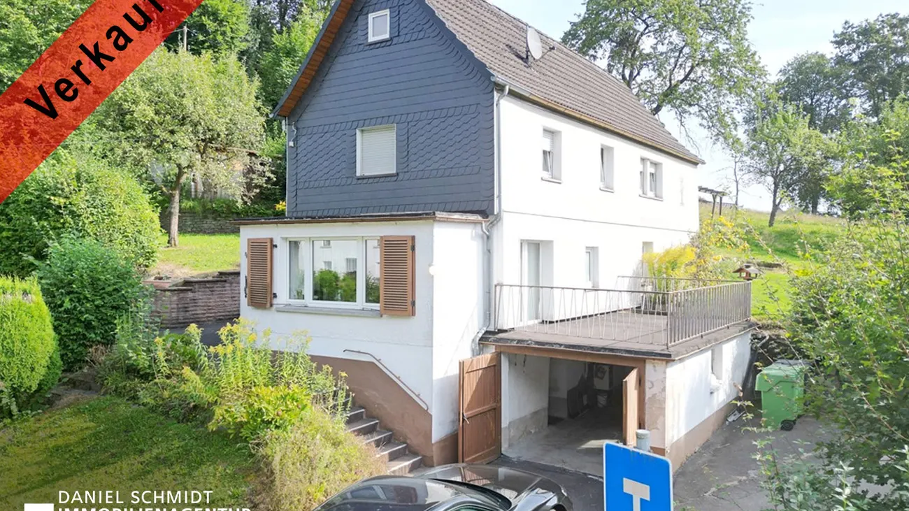 Einfamilienhaus mit Schieferfassade an einem Hang im Oberbergischen Kreis, davor der Schriftzug „Verkauft“.